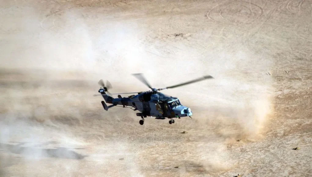 An 847 NAS Wildcat throws up sand and dust as it comes into land