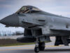 Close-up of a gray military fighter jet with RAF roundel on the fuselage, parked on a runway.