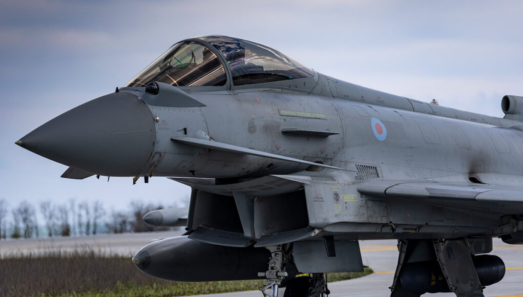 Close-up of a gray military fighter jet with RAF roundel on the fuselage, parked on a runway.