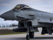 Close-up of a gray military fighter jet with RAF roundel on the fuselage, parked on a runway.