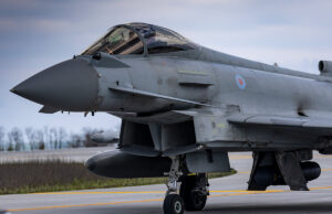 Close-up of a gray military fighter jet with RAF roundel on the fuselage, parked on a runway.
