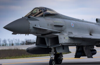 Close-up of a gray military fighter jet with RAF roundel on the fuselage, parked on a runway.