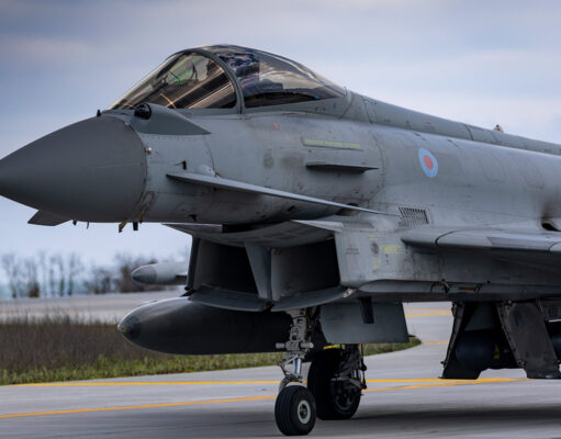 Close-up of a gray military fighter jet with RAF roundel on the fuselage, parked on a runway.