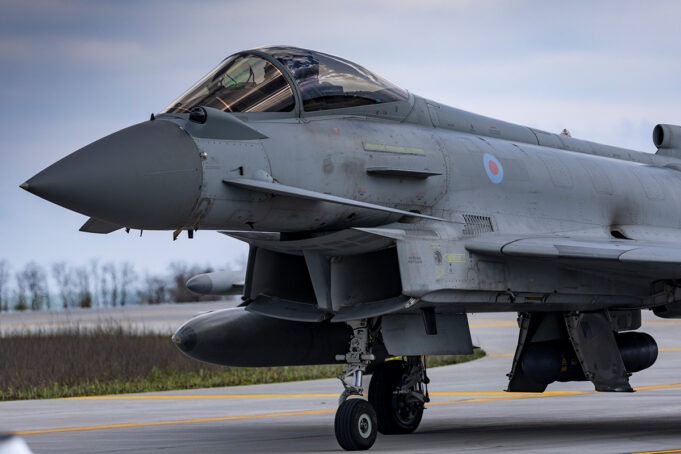 Close-up of a gray military fighter jet with RAF roundel on the fuselage, parked on a runway.