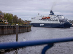 DFDS cruise ship moored in a harbor, viewed from a walkway with a blue railing in the foreground.