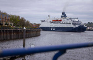 DFDS cruise ship moored in a harbor, viewed from a walkway with a blue railing in the foreground.