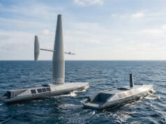 Two autonomous saildrone vessels ride the open ocean, one with a tall mast and a horizontal sail and the other nearby, horizon in the distance.