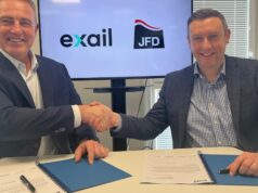 Two men in blazers shake hands over a table while signing documents, with Exail and JFD logos on screen behind them.
