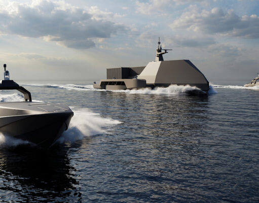 Large angular naval vessel gliding on calm sea with two smaller speedboats nearby under a cloudy sky, creating white wake.