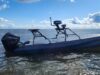 Gray small boat with a Mercury outboard powered engine on open water under a blue sky with clouds.