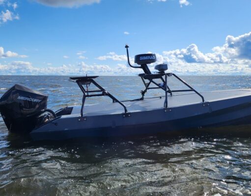Gray small boat with a Mercury outboard powered engine on open water under a blue sky with clouds.