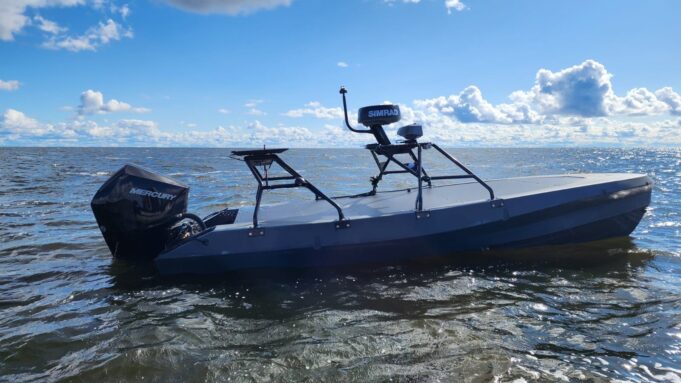 Gray small boat with a Mercury outboard powered engine on open water under a blue sky with clouds.