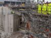 First Sea Lord visits Babcock Devonport site to view work Construction site with workers in high-visibility suits and hard hats on scaffolding above a deep concrete excavation pit.