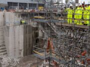 First Sea Lord visits Babcock Devonport site to view work Construction site with workers in high-visibility suits and hard hats on scaffolding above a deep concrete excavation pit.