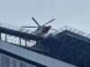 Emergency helicopter parked on a rooftop helipad above a modern glass office building