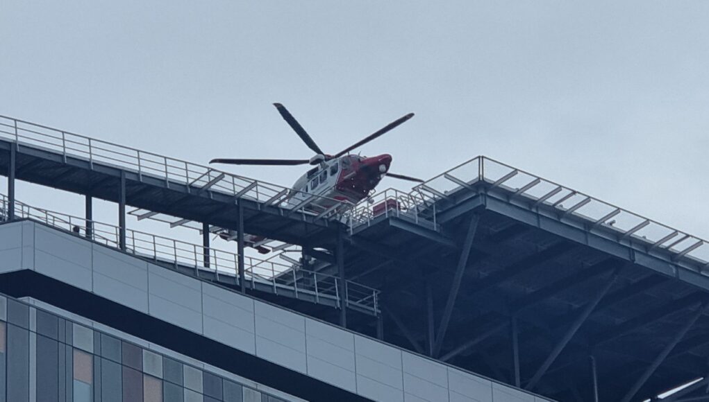 20240616_154031 Emergency helicopter parked on a rooftop helipad above a modern glass office building