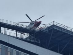 Emergency helicopter parked on a rooftop helipad above a modern glass office building
