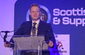 UK sets out how the 50m Scotland defence deal will be spent Man in a dark suit giving a speech at a clear podium with microphones, blue stage backdrop reading 'Scottish & Supply' and event signage nearby