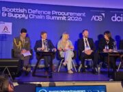 Primes pledge to open doors for Scottish SMEs at DPRTE Panel of six speakers seated on a stage at the Scottish Defence Procurement & Supply Chain Summit 2026, with a blue backdrop and sponsor logos behind them.