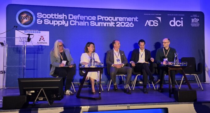 Primes say supply chain must change at DPRTE Scotland Five panelists seated on stage at the Scottish Defence Procurement & Supply Chain Summit 2026, with a blue-lit backdrop and sponsor logos.