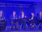 Five panelists seated on stage during the Scottish Defence Procurement & Supply Chain Summit 2026, blue-lit backdrop with sponsor logos.