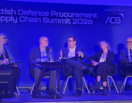 Five panelists seated on stage during the Scottish Defence Procurement & Supply Chain Summit 2026, blue-lit backdrop with sponsor logos.