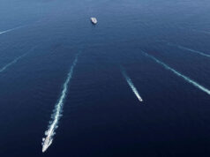 All ten JEF nations sign up to British northern navies plan Aerial view of several ships at sea leaving white wake trails that intersect on the deep blue ocean.