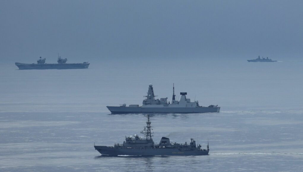 20260523_114217 Formation of three gray warships sailing on a calm blue sea with a hazy horizon.