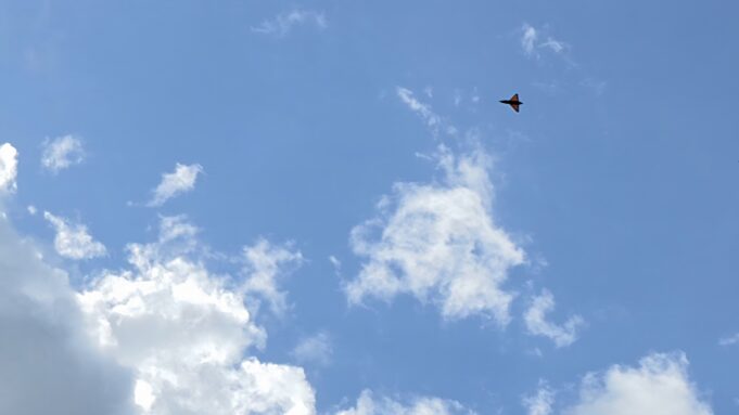 NATO accelerates counter-drone testing and capacity Small orange delta-wing aircraft flying through a clear blue sky with a few clouds (distant plane).