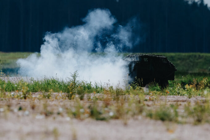 NATO looks to civil industry to scale drone production Smoke rising from a dark, rusted barbecue in a grassy field, with a tree line in the distance.