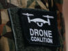 The NATO Innovation Badge Close-up of a black Velcro patch with a white winged emblem on camouflage military uniform.