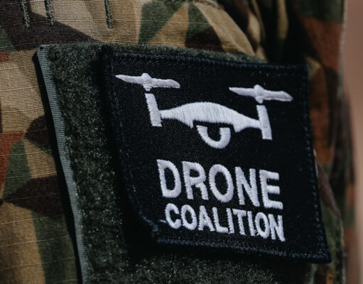The NATO Innovation Badge Close-up of a black Velcro patch with a white winged emblem on camouflage military uniform.