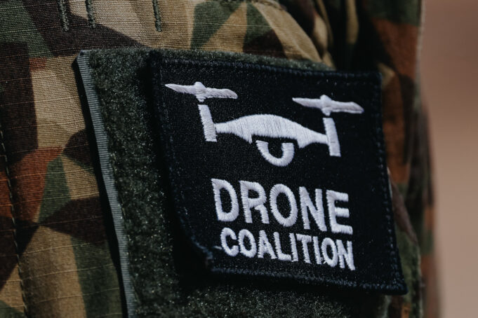 The NATO Innovation Badge Close-up of a black Velcro patch with a white winged emblem on camouflage military uniform.