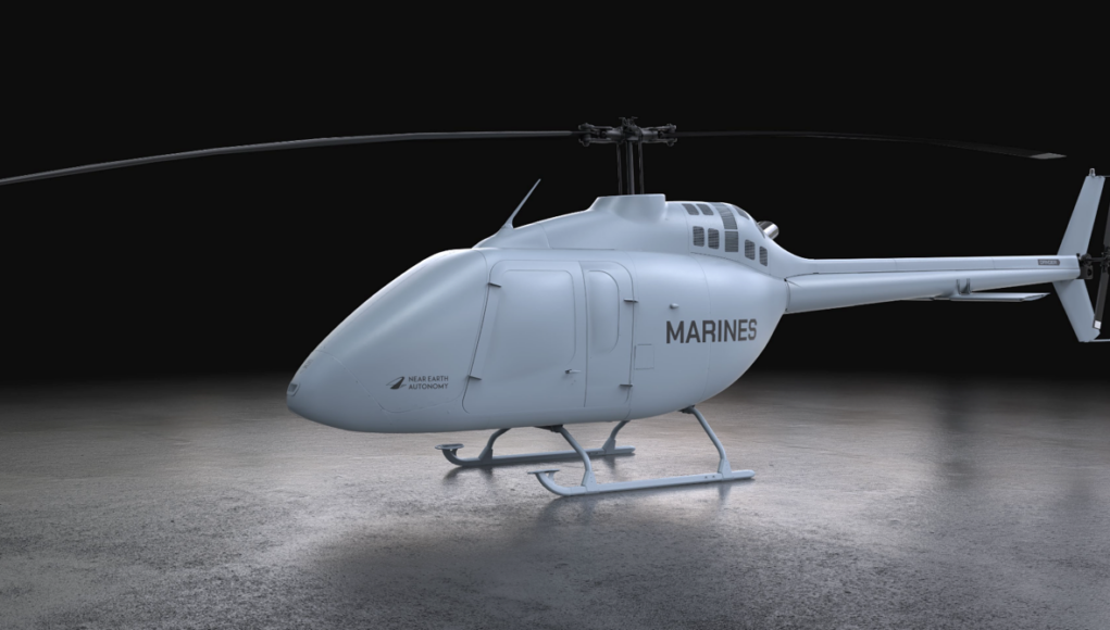 Light gray Marine helicopter with 'MARINES' on the side, parked on a concrete floor in a dark studio.
