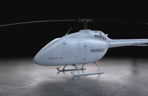 Light gray Marine helicopter with 'MARINES' on the side, parked on a concrete floor in a dark studio.