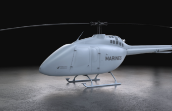 Light gray Marine helicopter with 'MARINES' on the side, parked on a concrete floor in a dark studio.