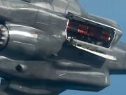 F-35B completes first flight with British SPEAR 3 missile Close-up of a damaged metallic sculpture resembling a fighter jet, with jagged edges and exposed orange interior components against a blue sky.