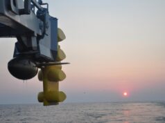 Canada picks Thales S2087 sonar for River-class ships Close-up of a blue offshore platform component with yellow stabilizers hanging over a calm sea at sunset.