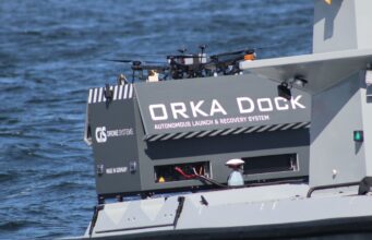 Orka Dock autonomous launch and recovery system on a gray watercraft, with drones on top and the text 'Orka Dock' visible on the side