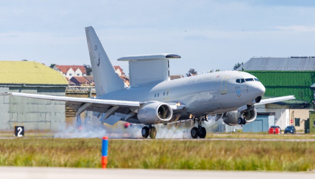 E7_Wedgetail_Arrival_Original_Image_m59643 RAF transport aircraft lifting off from runway at an airbase with hangars and buildings in the background