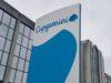 Capgemini corporate sign with blue curved graphic on a tall white panel beside a glass-front building exterior