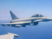 Royal Air Force Eurofighter Typhoon in flight over the sea, with underwing weapons and drop tanks visible.