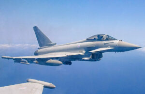 Royal Air Force Eurofighter Typhoon in flight over the sea, with underwing weapons and drop tanks visible.
