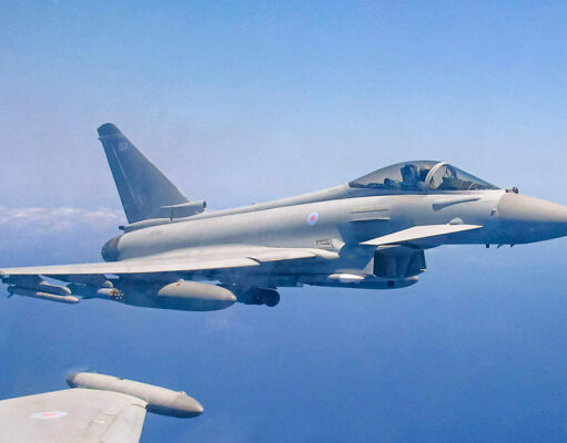 Royal Air Force Eurofighter Typhoon in flight over the sea, with underwing weapons and drop tanks visible.