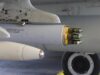 Close-up of a wing-mounted rocket launcher under a military aircraft, showing yellow-tipped missiles ready for launch