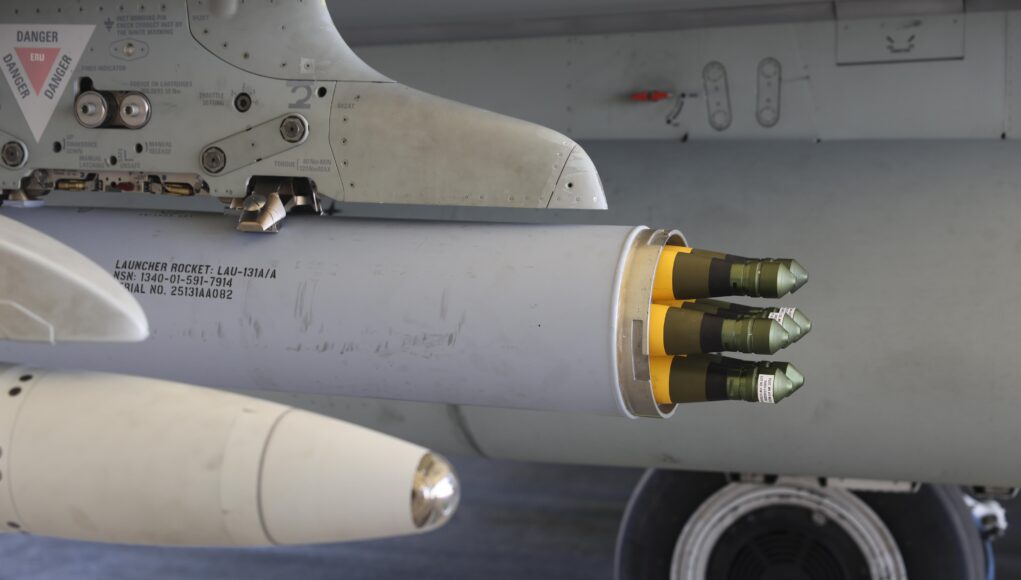 Advanced Precision Kill Weapon System Close-up of a wing-mounted rocket launcher under a military aircraft, showing yellow-tipped missiles ready for launch