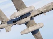 Military unmanned drone in flight with its open payload bay visible.