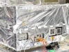 Reflective-wrapped satellite instrument in a cleanroom, with exposed control panels and orange cables visible.