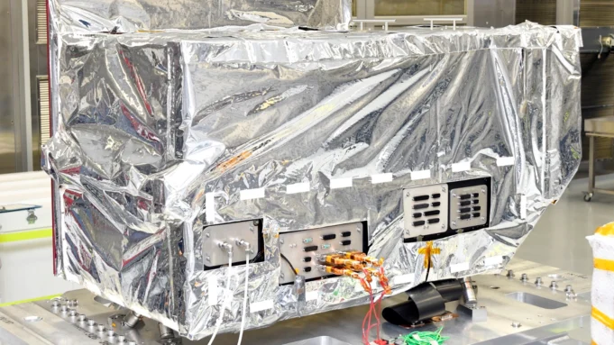 BAE delivers sensor hardware for Space Force satellite Reflective-wrapped satellite instrument in a cleanroom, with exposed control panels and orange cables visible.