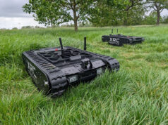 Army awards first fast-tracked UGV contract to UK startup Two black tracked robots with antennas sit in a tall-grass field, one foreground and one in the background, labeled XRC Robotics.